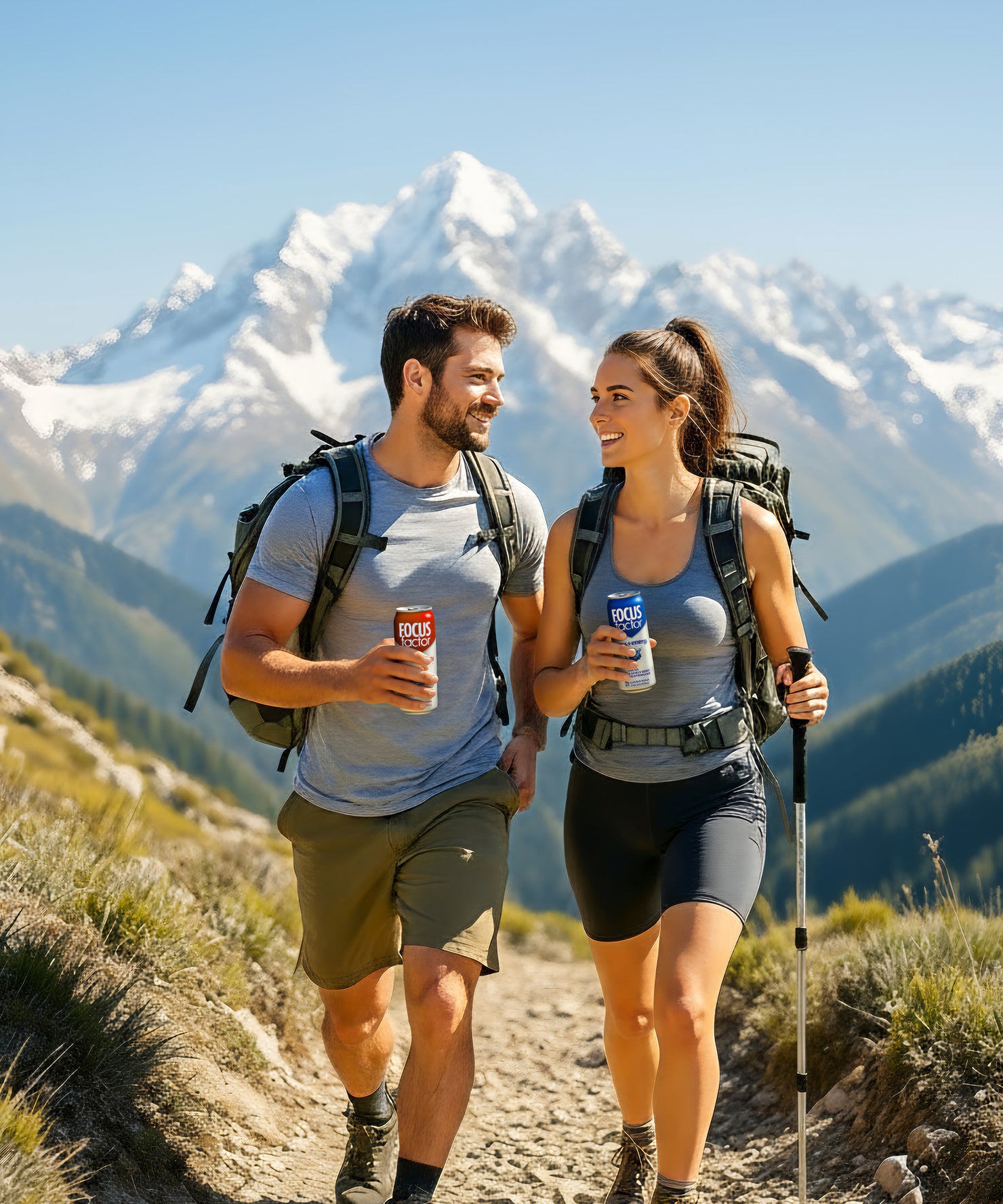 Two hikers with backpacks and cans of Focus Factor's Focus + Energy Drinks on a mountain trail with snow-capped peaks in the background.